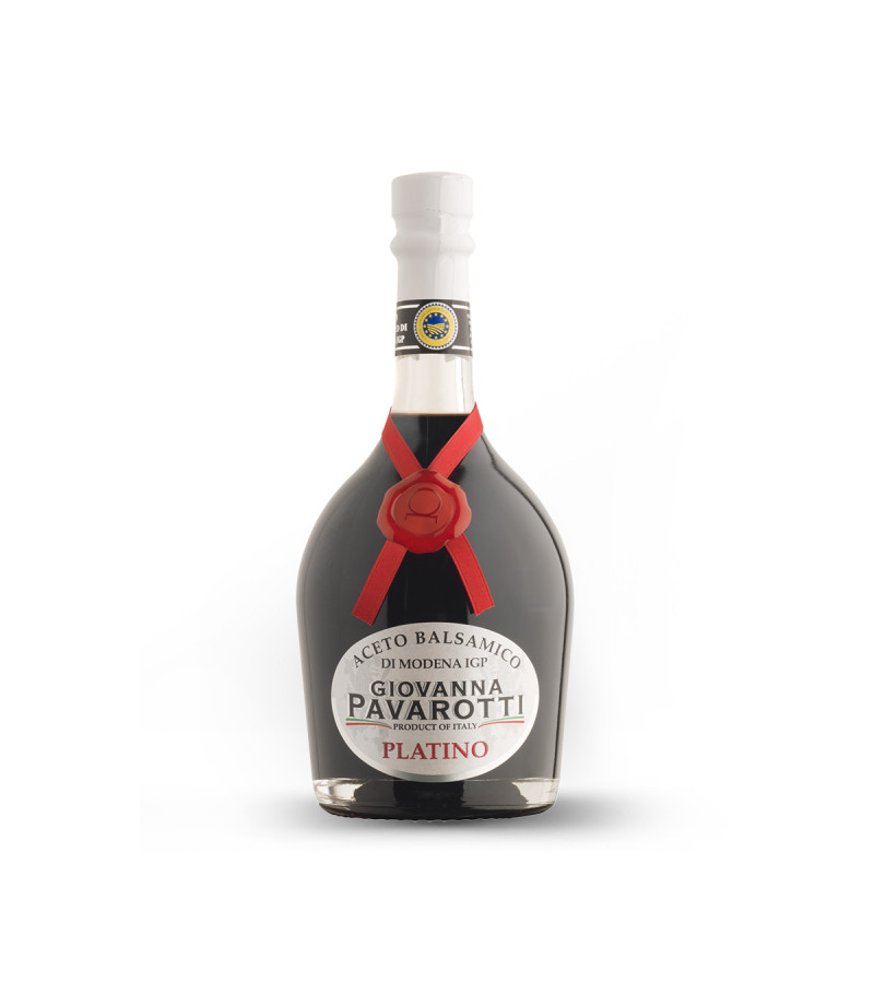 Vinaigre Balsamique de Modène Giovanna Pavarotti Platino 25cl, la bouteille donne un aspect haut de gamme, avec des couleurs qui contraste très bien, un bouchon et une étiquette blanche, sur le bouchon on voit le logo IGP, sur l'étiquette on voit le nom du vinaigre, son appellation. Autour de la bouteille et descendant en profitant de la rondeur de la bouteille, un petit ruban rouge avec un sceau rouge.